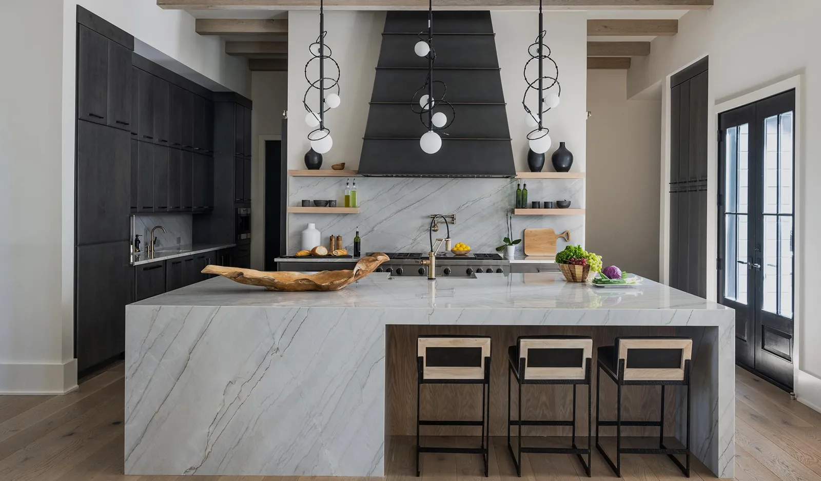 Mouser kitchen with dark cabinetry, open shelving, and a marble waterfall island
